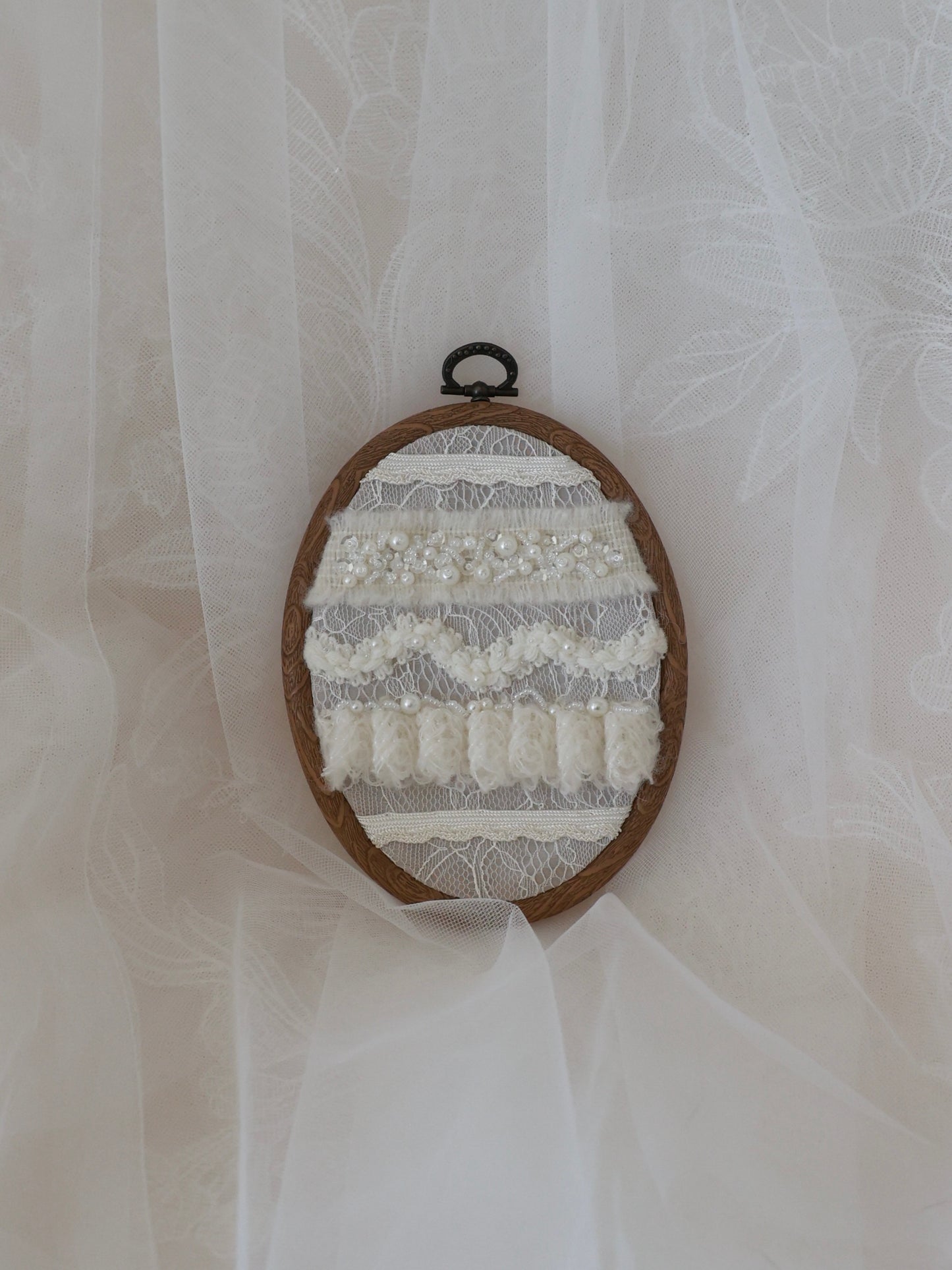 Embroidery hoop with lace and fabric patterns on a sheer white curtain background