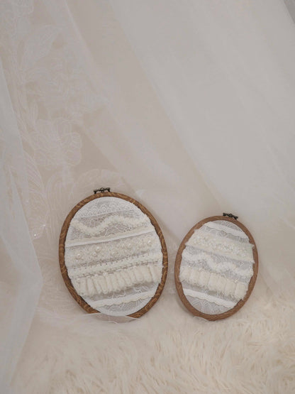 Two round embroidered pieces in wooden frames on a textured white background