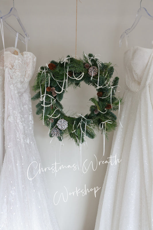 Christmas wreath hanging between two white dresses with text 'Christmas Wreath Workshop'.