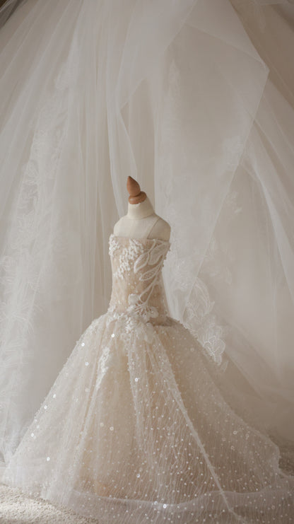 Close-up of a wedding dress with intricate details and a flowing train.