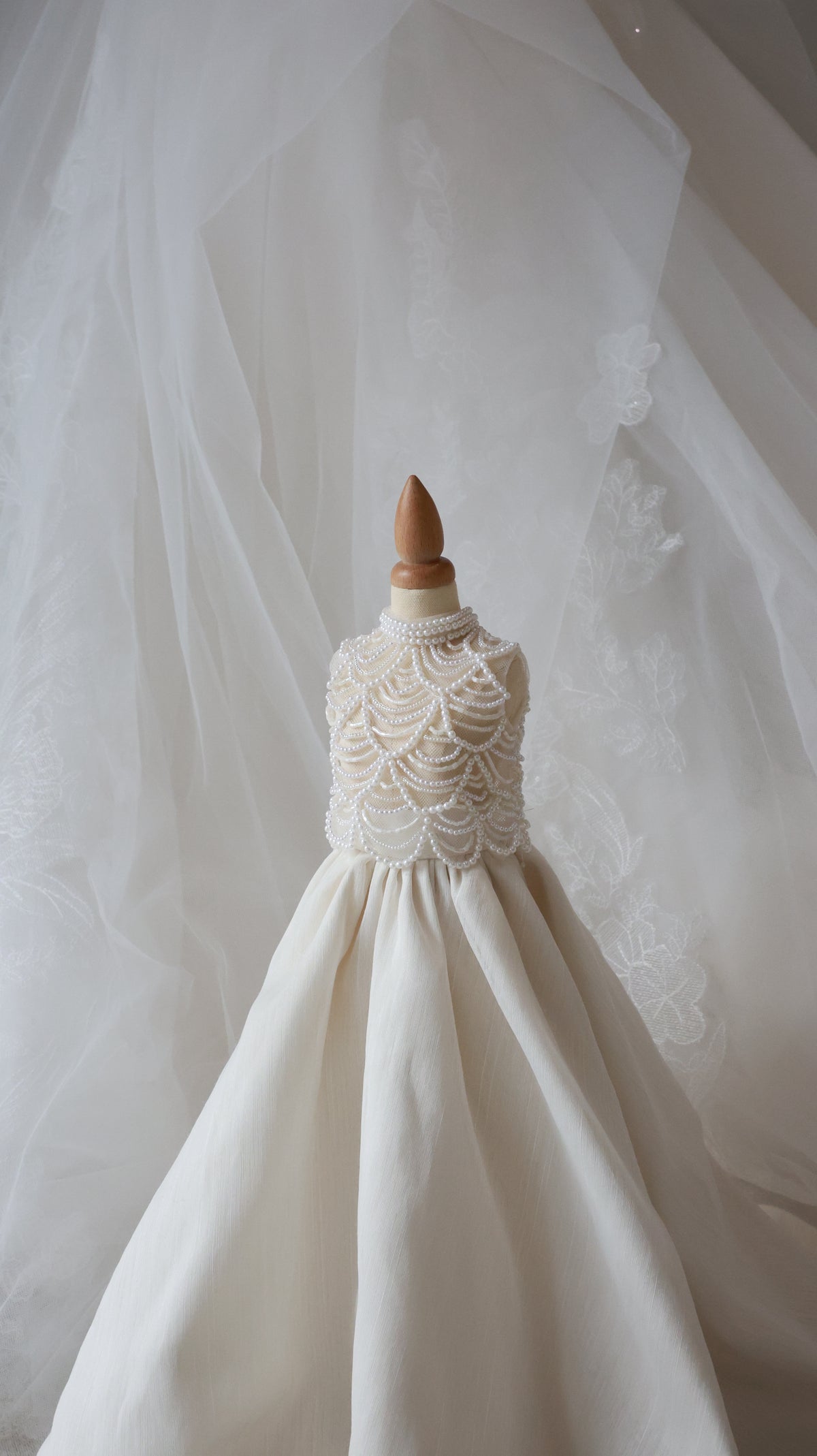 Close-up of a white wedding dress with lace detailing on a neutral background