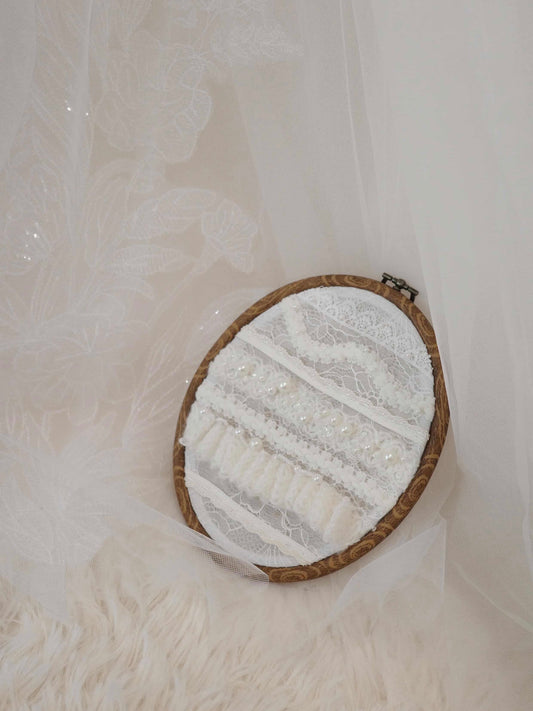 Embroidery hoop with lace and beads on a soft white background