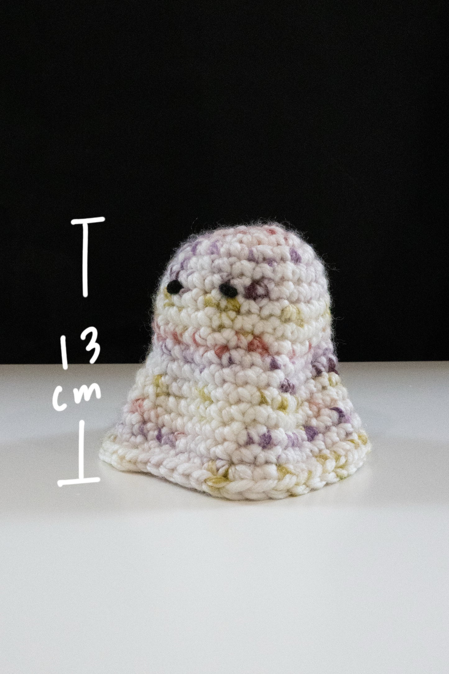 Crocheted little ghost figure measuring 13 cm, featuring pastel colors and cute face, perfect for Halloween decor.