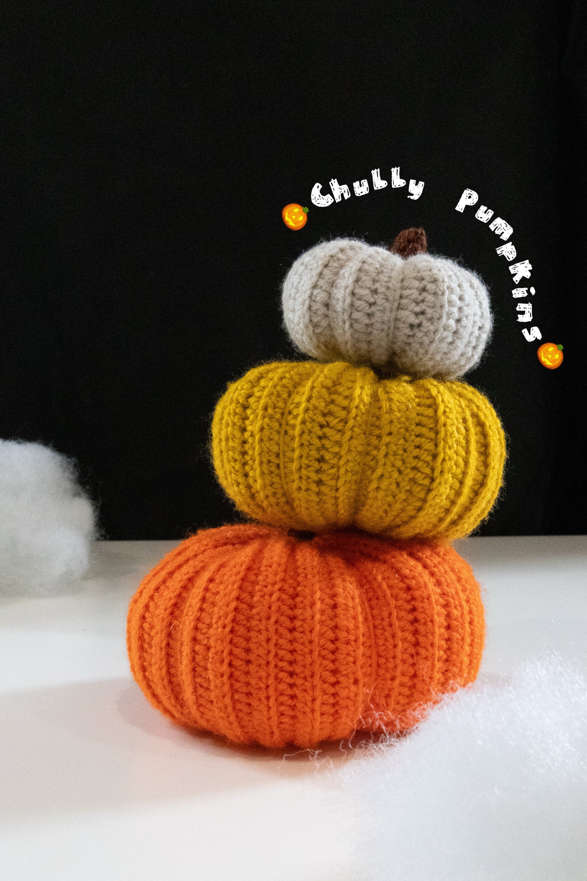 Stack of chubby crocheted pumpkins in orange, yellow, and white for Halloween decor.