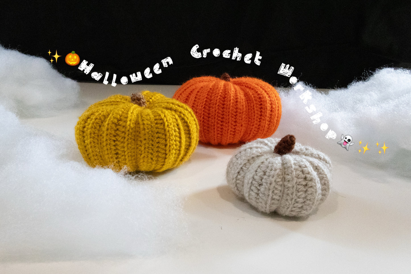 Crochet workshop pumpkins: yellow, orange, and gray chubby pumpkins on white fabric background.