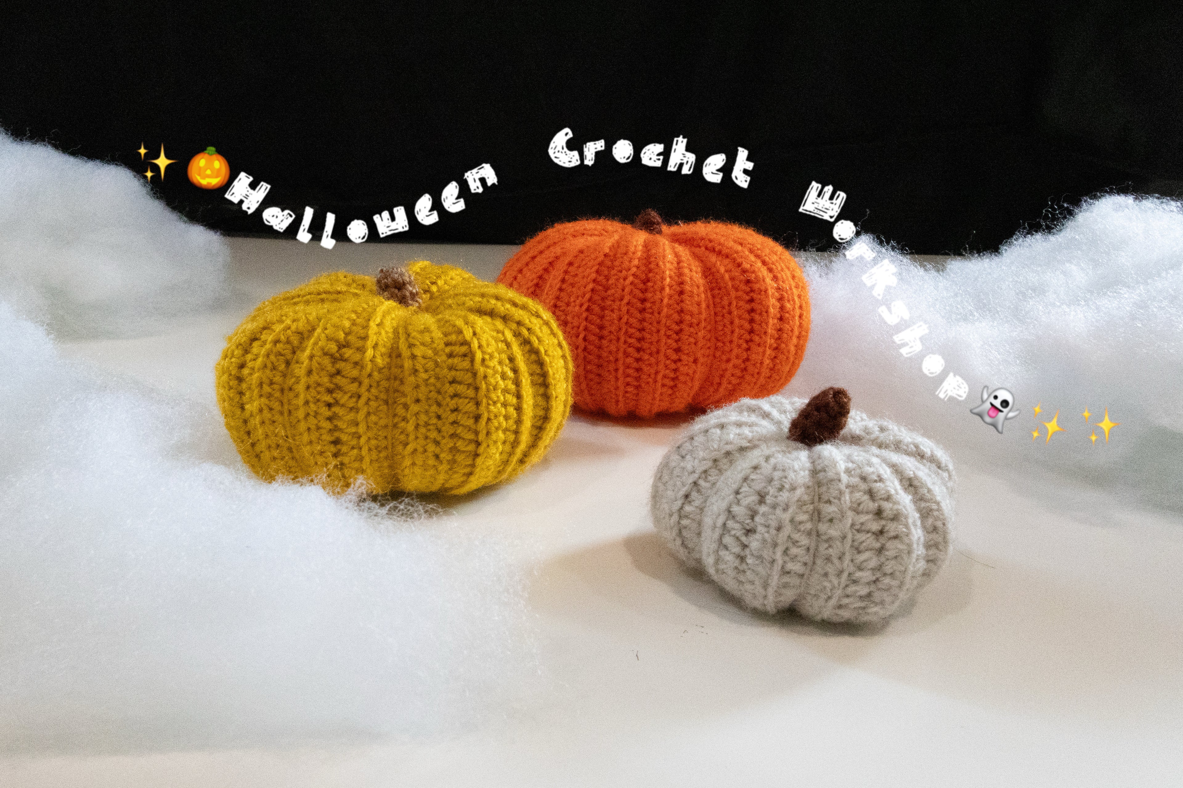 Crochet workshop pumpkins: yellow, orange, and gray chubby pumpkins on white fabric background.