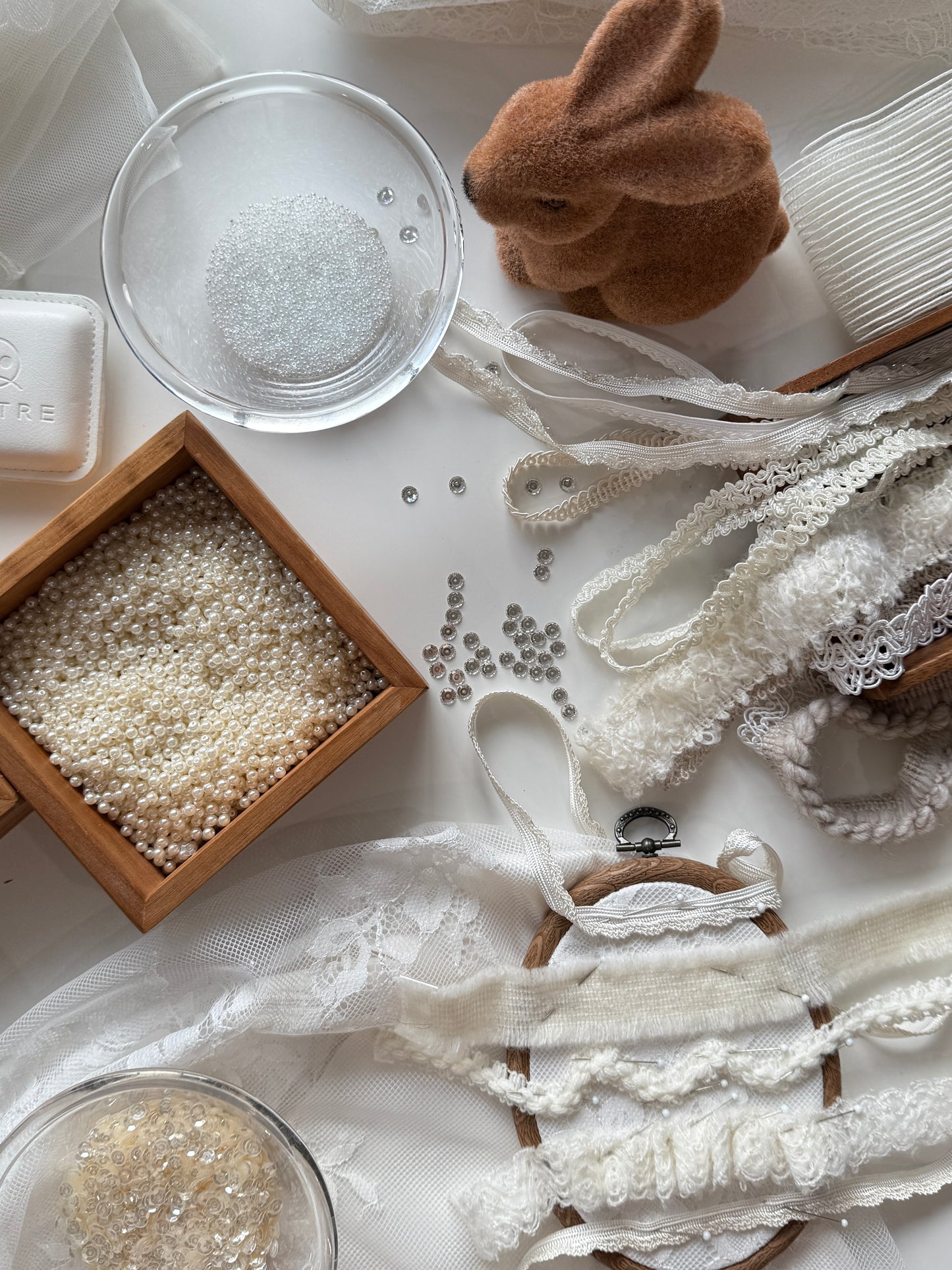 Decorative items including lace, beads, and a small rabbit figurine on a white surface.