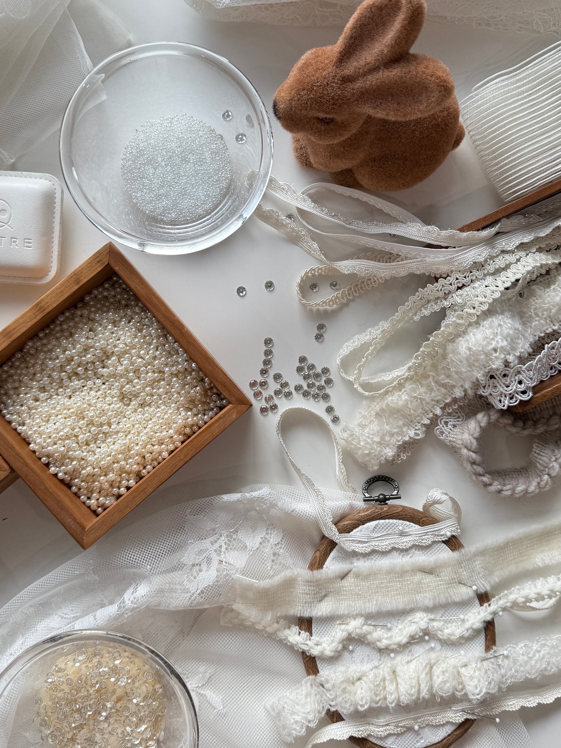 Decorative items including lace, beads, and a small rabbit figurine on a white surface.
