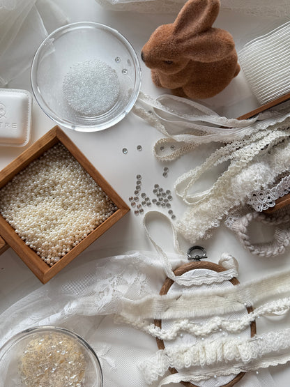 Decorative items including lace, beads, and a small rabbit figurine on a white surface.
