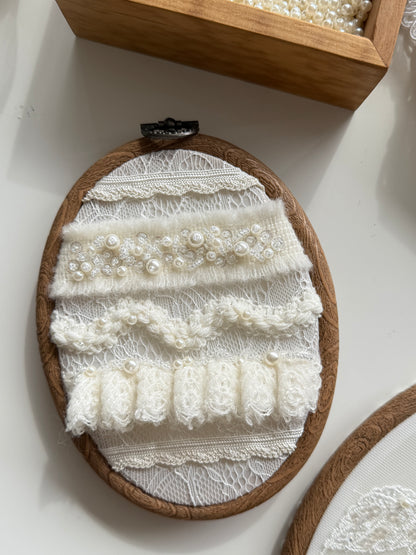 Embroidery hoop with lace and pearl details on a white surface
