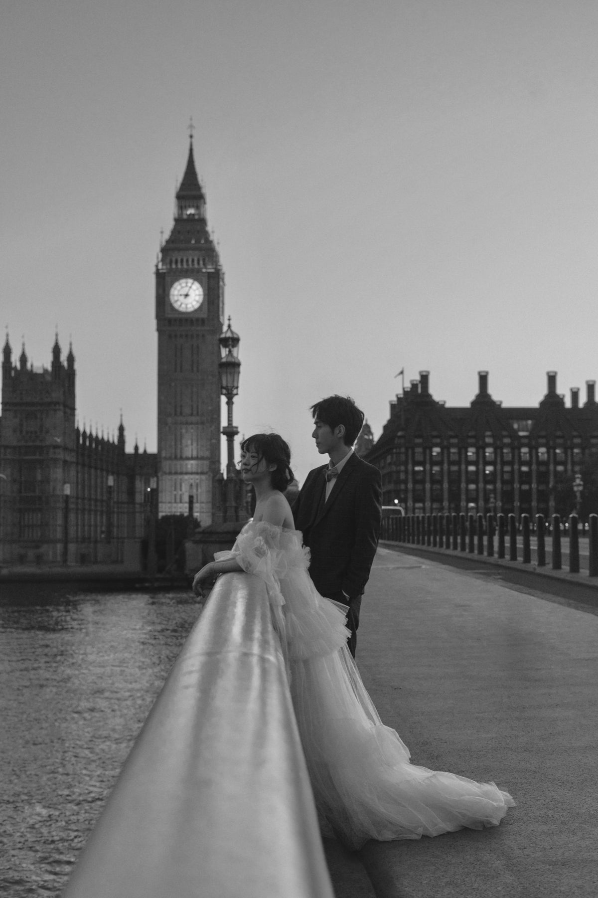 Black and white wedding photograph of a bride and groom standing on Westminster Bridge with Big Ben and the Houses of Parliament in the background.