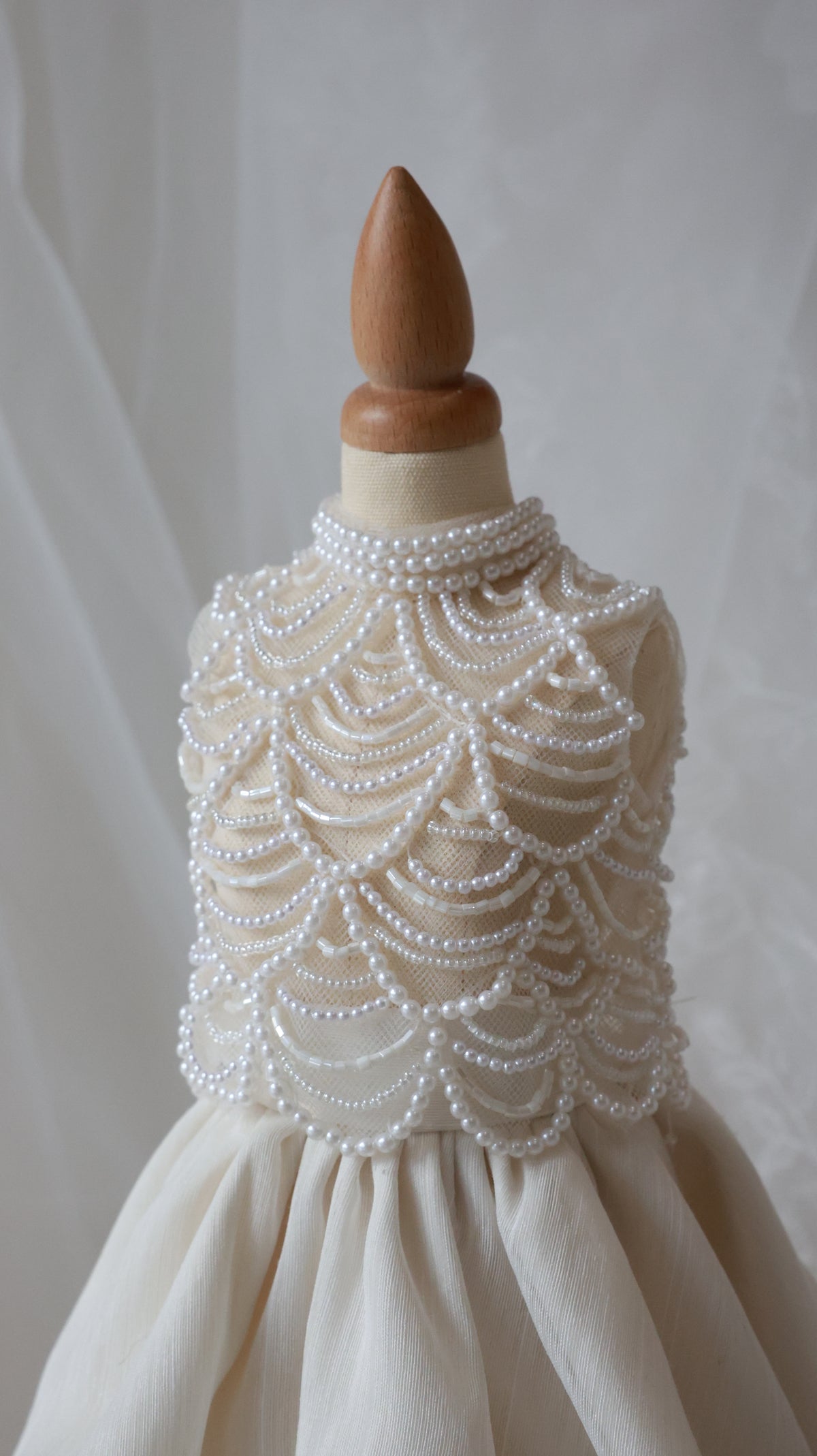 White dress with intricate beadwork on a mannequin against a plain background