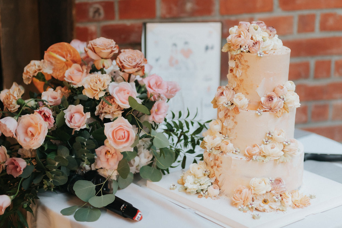 Romantic London wedding styling with a three-tier floral wedding cake and blush pink, peach and ivory flower arrangement.